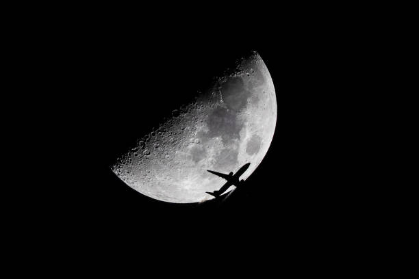 Commercial airliner crossing the moon at night