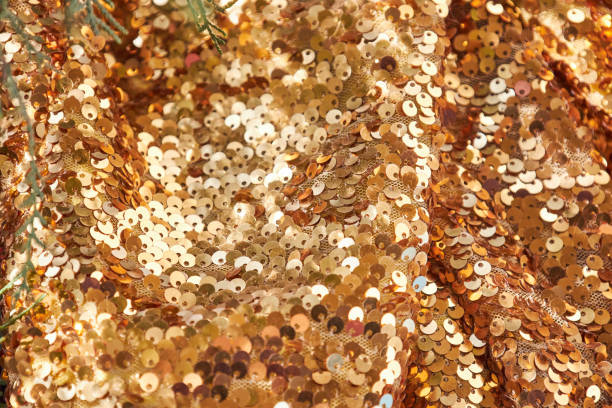 Waves of brightly shiny fabric with large gold sequins. Festive rich textiles glitter mesh for dresses. Yellow texture new year background.