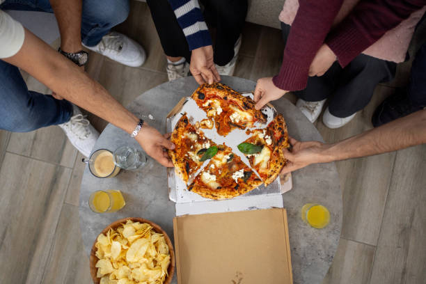istock Friends sharing pizza and potato chips at home 2203749823