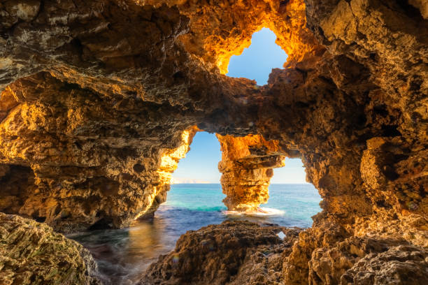 istock Sunlit sea cave with ocean view, rugged cliffs, and crystal waters, Cueva de Los Arcos, Moraig, Spain 2203750306