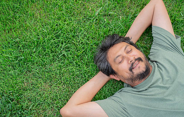 istock Top view portrait of handsome man with a beard relaxing lying on the grass. 2203751249