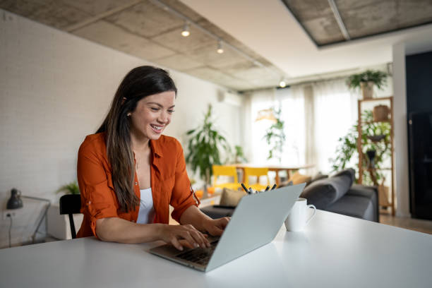 istock Young woman working from home on laptop and smiling 2203753396
