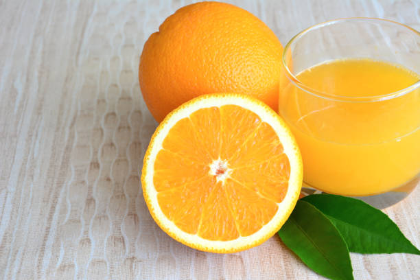 a close up of Fresh Orange Juice with some oranges