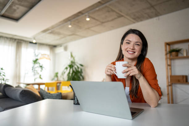 istock Happy freelancer woman drinking coffee while working from home 2203753502