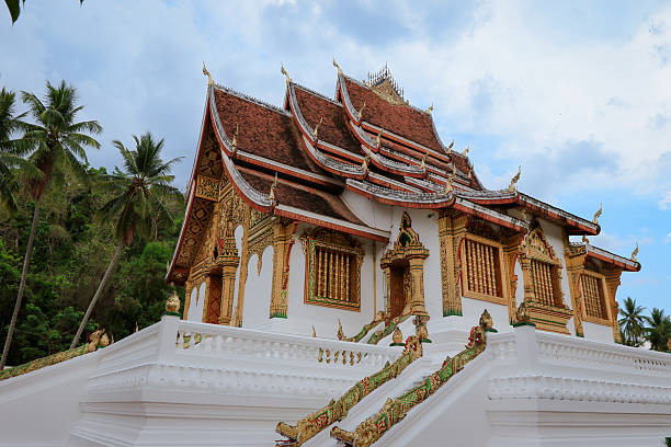A stunning temple in Luang Prabang showcases elaborate designs amidst a tranquil natural setting. Visitors admire its beauty.