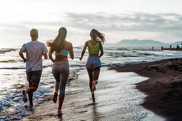 istock Group running on beach jogging having fun training. Exercising runners training outdoors 2203759017