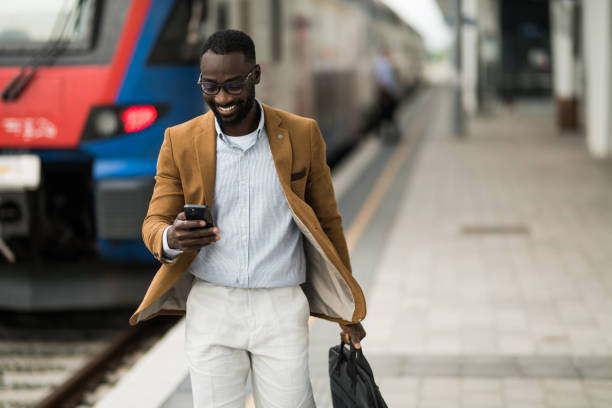 istock Cheerful black businessman using smart phone after arriving on railway station. 2203762295