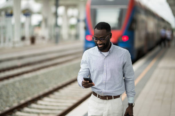 istock Cheerful black businessman using smart phone after arriving on railway station. 2203762583