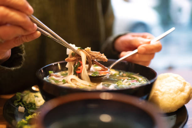 istock Woman eating Vietnamese dish Pho soup in a cafe 2203762687