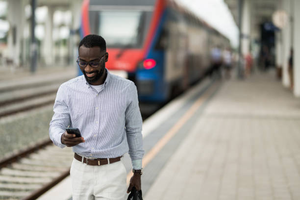 istock Cheerful black businessman using smart phone after arriving on railway station. 2203763046