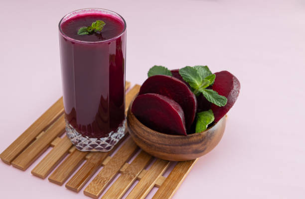istock Beet smoothie next to a wooden bowl with beet slices on a light background 2203765100