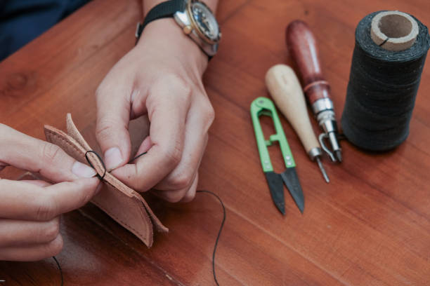 istock A closeup man hand with threads and needle , making leather goods with handstitched process in wooden table 2203765308