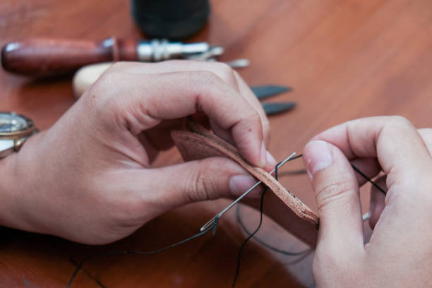 istock A closeup man hand with threads and needle , making leather goods with handstitched process in wooden table 2203765396
