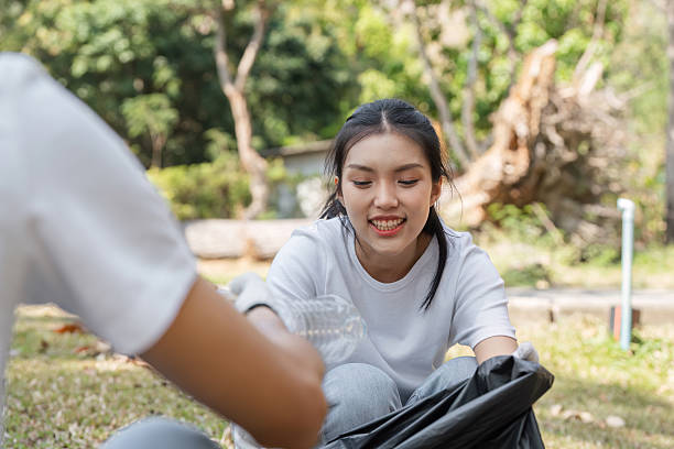 istock Young woman enjoying a community cleanup while collecting plastic waste 2203770345