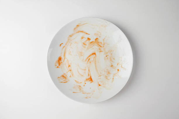 istock Dirty plate isolated, empty bowl after dinner, ready lunch, smeared ketchup sauce on white plate background, top view 2203772554