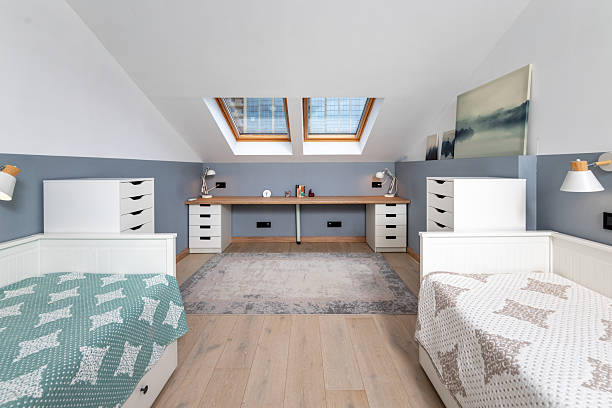A bedroom with two twin beds and a desk. The room is very clean and organized. The white bed is on the left side of the room, and the other bed is on the right side
