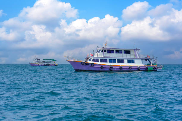 istock Two colorful boats float gently on clear blue waters, surrounded by a bright sky filled with fluffy clouds. The scene captures a peaceful coastal moment in daylight. 2203774884