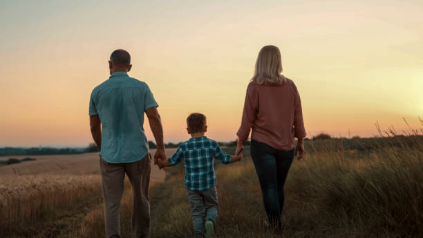 istock Young Boy with Parents Strolling in Sunset Wheat Field 2203778256