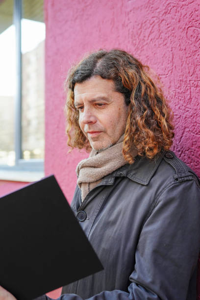 istock mature man reading a book in red background. Saint George's day 2203778859