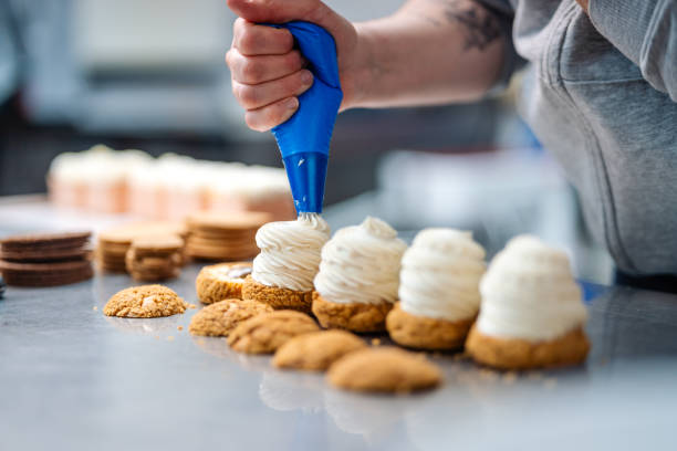 Professional pastry chef decorating delicate desserts with piped cream in sleek culinary workspace