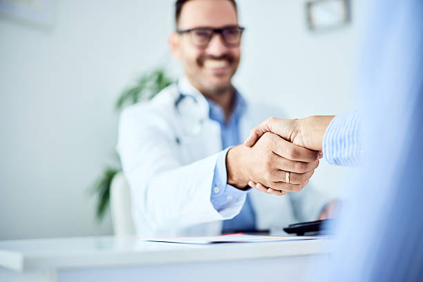 istock Doctor and Patient Handshake at Appointment in Professional Office Workspace 2203780544