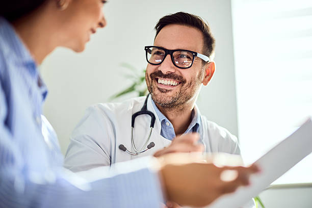 Smiling Male Doctor Conversing with a Patient in a Bright Office Setting stock photo