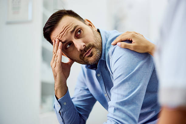 Worried Man Comforted by a Supportive Hand in a Bright Office