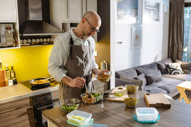istock Man preparing meal in a modern kitchen and packing in a food containers 2203781399