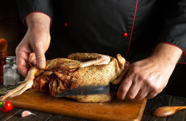 istock A chef skillfully slices a well-seasoned bird on a wooden cutting board. The rustic kitchen setting features herbs and spices, showcasing culinary expertise and preparation 2203782914