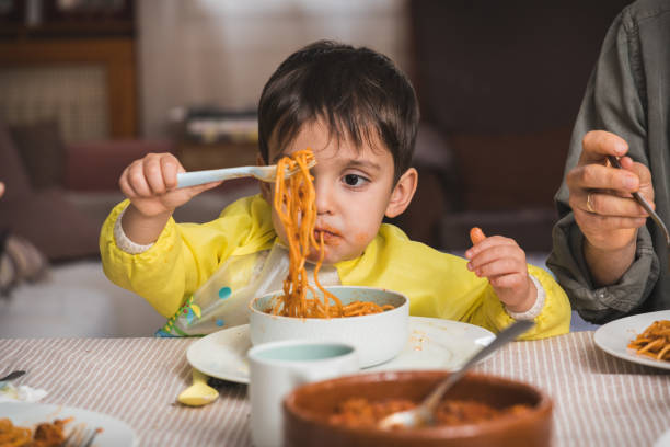 istock Cheerful Little Boy Holding Up Spaghetti with a Funny Expression 2203783815