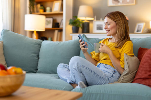 istock Happy woman using smartphone while relaxing at home 2203783918