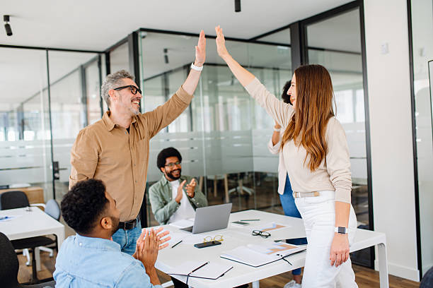 istock A diverse group of professionals in a modern office celebrates success with a high-five 2203784063