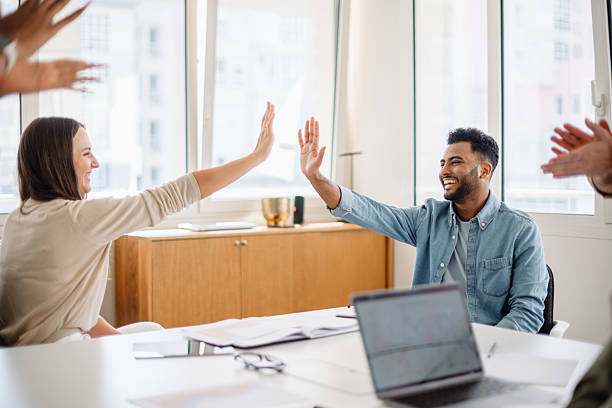 istock A diverse group of professionals in a modern office celebrates success with a high-five 2203784073