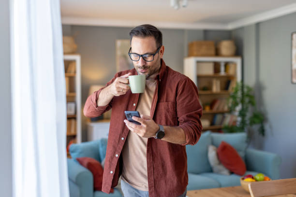istock Man Enjoying Coffee While Texting in Cozy Living Room 2203785012