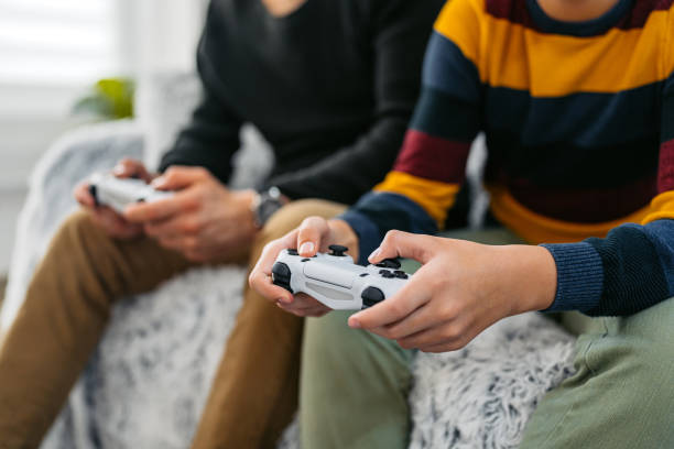 Father and son playing video games together on a joystick at home. Close-up.