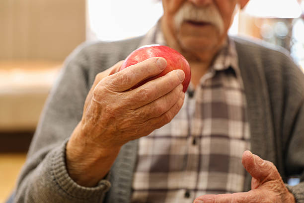 istock A Gentle Grip: An Old Man Holding a Red Apple in a Nursing Home 2203789153