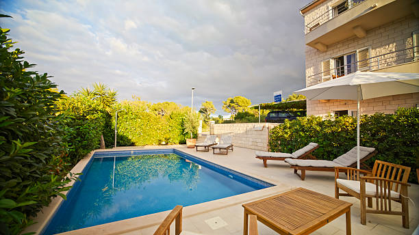 istock Bright Luxury Villa With Poolside Sun Loungers And Lush Greenery Under Partly Cloudy Skies 2203789664