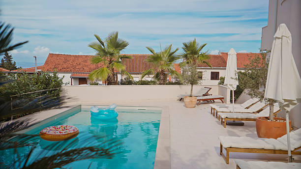 istock Sunny Private Pool with Palm Trees and Lounge Chairs on a Relaxing Day 2203789933