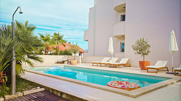 istock Serene Private Poolside with Cozy Lounge Chairs and Floating Inflatable in Bright Daylight 2203789939