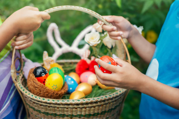 istock Children holding a basket of Easter eggs outdoors in bunny ears 2203791272