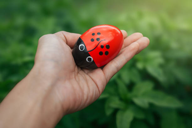 Red Easter eggs in a palm with a soft green bush background with golden sunlight shining.