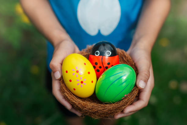 Children holding a basket of Easter eggs outdoors in bunny ears.