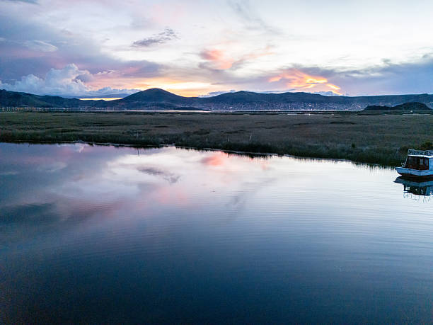 Tranquil lake mirroring a vibrant sunset sky with mountains in the background. Peaceful landscape setting at dusk. Nature's beauty in a serene, reflective scene.