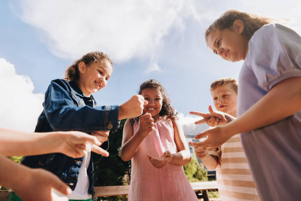 istock Group of children playing rock-paper-scissors in a park setting 2203803896