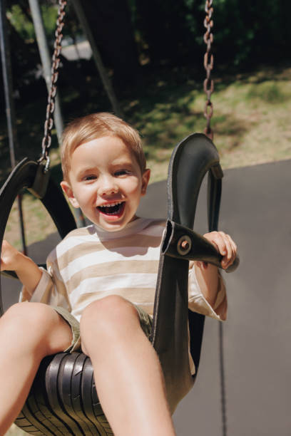 istock Smiling child swinging outdoors on a sunny day in the park 2203804105