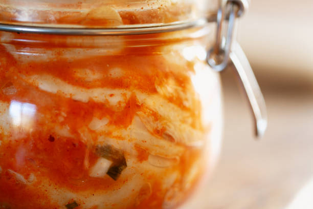 extreme close-up of a jar with kimchee, bubbles of fermentation process visible