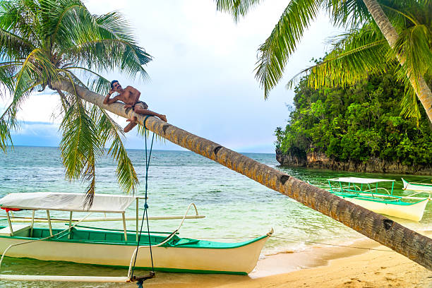 istock Man relaxing on palm tree on kangbangyo island, siargao, philippines 2203808578