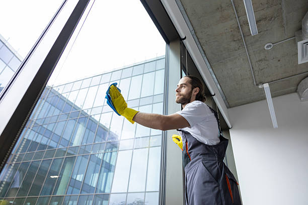 istock Young service man cleaning windows in the office and looking busy 2203809349