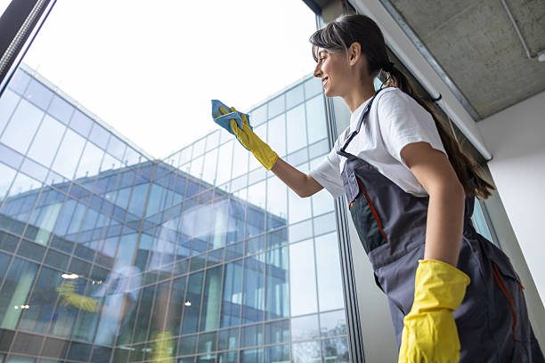 Woman cleaning apartment window on stool with rag, cleaning house or apartment as concept of housework and home chores for new building space.