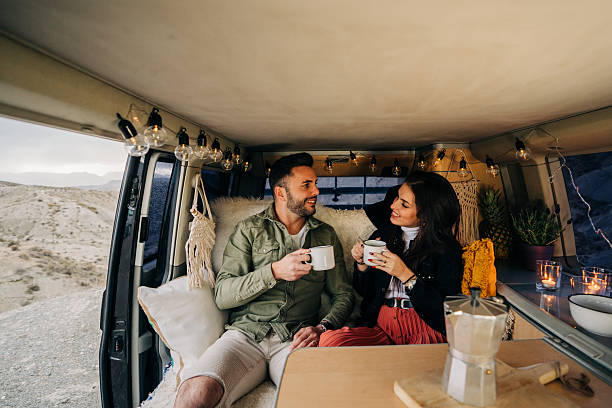 istock Couple enjoying coffee inside cozy camper van during road trip 2203812440
